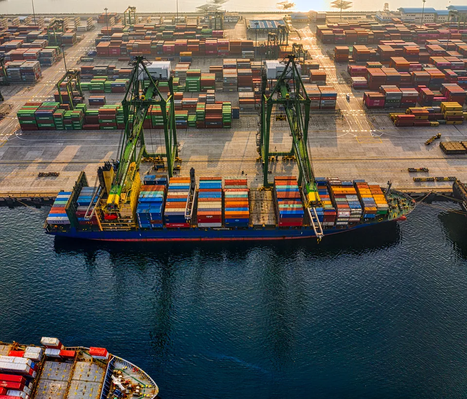 Vista aérea de un buque portacontenedores junto a grúas y contenedores en una terminal marítima